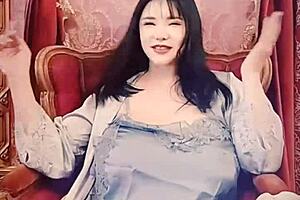 Japanese woman in blue satin performs solo on webcam.