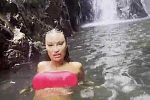 Monika Fox in pink top and yellow shorts, walking through jungle and waterfalls, feeling free.